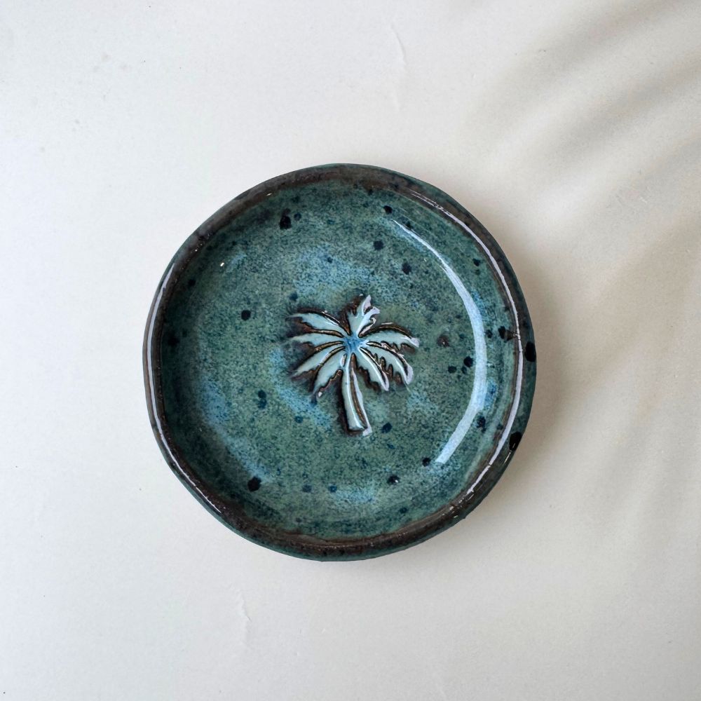 Ceramic trinket dish with a palm tree design on a white background